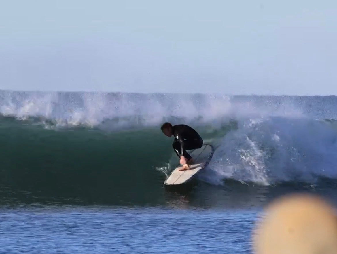 Person surfing on a wave with clear sky and water.